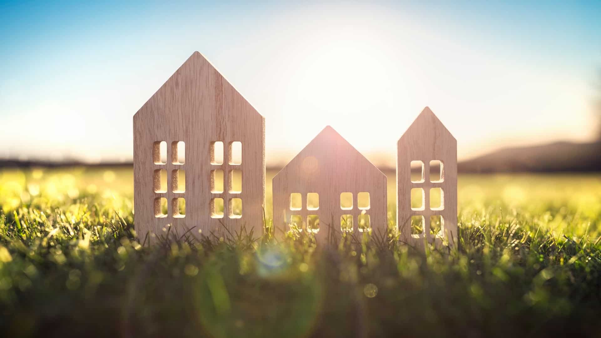 Ecological wood model house in empty field at sunset