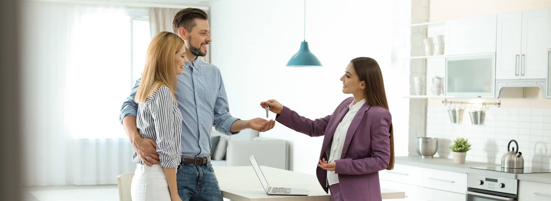 Female real estate agent giving house key to couple indoors