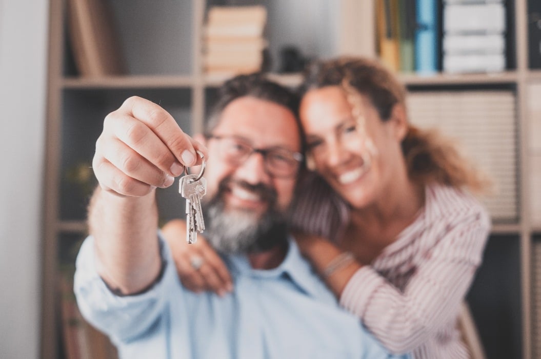 Focus on keys, held by excited young spouses homeowners. Happy married family couple celebrating moving in new house home , demonstrating keys, standing in apartment, real estate mortgage concept..