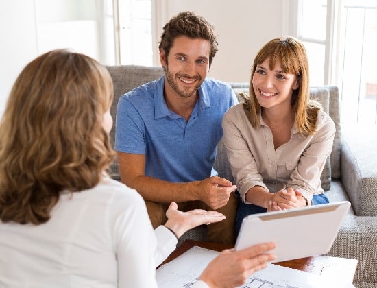 Real-estate agent presenting to a couple a project property on tablet PC