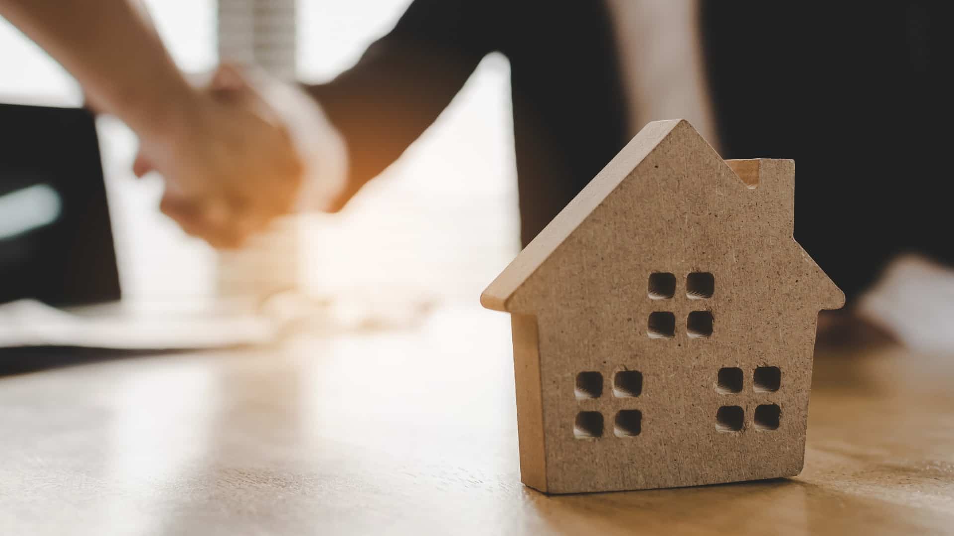 real estate broker manager hand shake to customer after signing contract for buying house in estate agent office behind House model, investment, home loan contract, buy and sell house concept