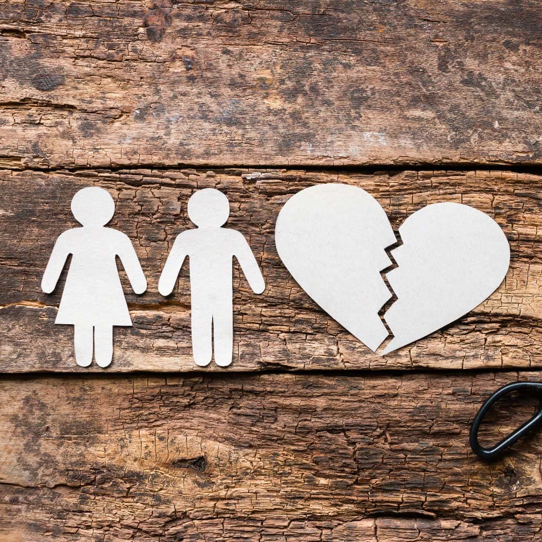 Divorced couple near a broken heart on a wooden background